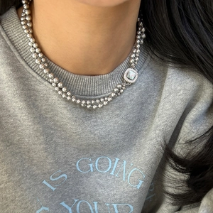 Detail of double-layer beaded necklace with square mother-of-pearl pendant on model