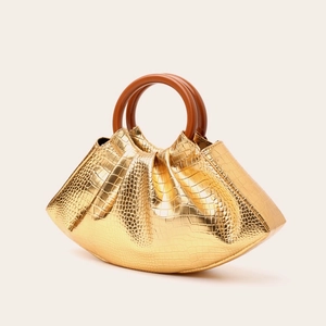 Detail of gold faux crocodile texture on cloud bag with round vintage wooden handle