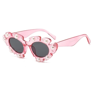 Fashionable women's pink resin sunglasses with pearl floral embellishments and grey lenses