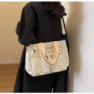 Detail of off-white corduroy crossbody bag with multiple zip pockets and adjustable strap