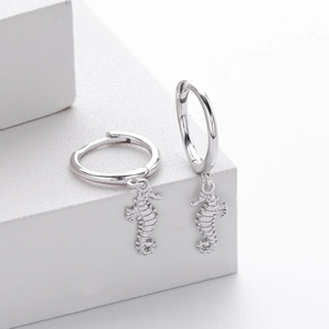 Detailed close-up of S925 sterling silver seahorse earrings on a minimalist white stone pedestal