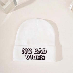Close-up of white knit beanie featuring black 'NO BAD VIBES' embroidery and fine texture