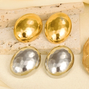 Close-up of gold and silver teardrop earrings with elegant hammered metal texture