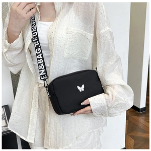 Close-up of black crossbody bag with white butterfly motif and stylish lettered wide strap