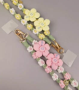 Detail of handmade woven macrame phone lanyards with daisy flowers and smile charms