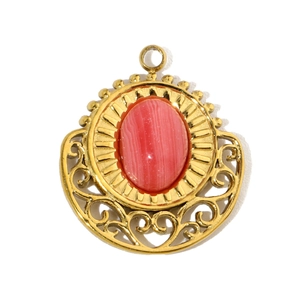 Macro detail of gold-plated pendant featuring an oval pink stone and filigree accents