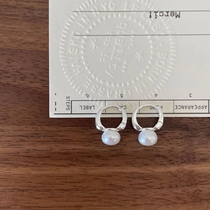 Elegant 925 sterling silver pearl hoop earrings presented on a rustic wood background