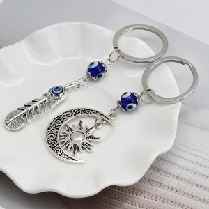 Dettaglio del portachiavi con piuma e occhio del diavolo su vassoio in ceramica bianca