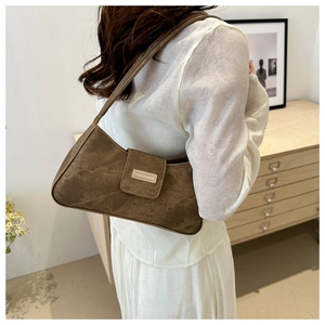 Detailed close-up of a brown suede underarm bag featuring a stylish metal clasp