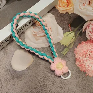 Close-up of pink and green braided phone lanyard with a handmade crochet flower charm