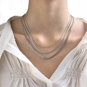 Detail shot of a layered three-piece stainless steel necklace set worn by a model