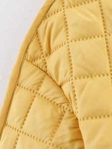 Detail shot of yellow quilted jacket fabric with premium square stitching pattern