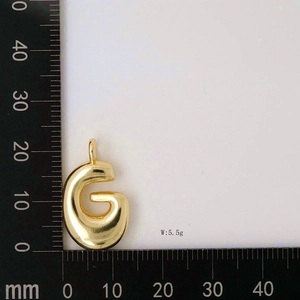 Macro view of gold balloon letter G pendant on ruler showing size and 5.5g weight