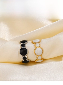 Macro shot of geometric enamel rings on silk showing gold and silver finishes