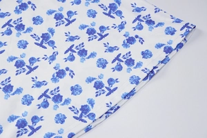 Detail of floral printed fabric with blue flower pattern on white summer dress