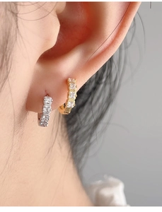 Close-up of gold and silver huggie earrings with cubic zirconia on a female model
