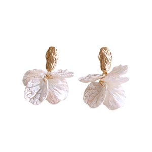 Elegant gold earrings with white acrylic petal pendants on a clean white background