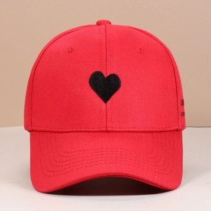 Close-up of red cotton baseball cap featuring black heart embroidery and side lettering