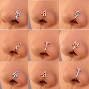 Close-up of zircon alphabet M A S T non-piercing nose clips in silver and rose gold finishes