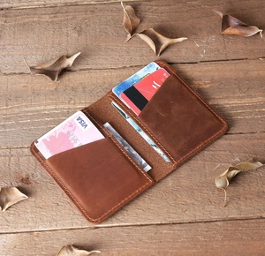Detail shot of a brown vintage leather card holder with multiple slots on a wooden desk