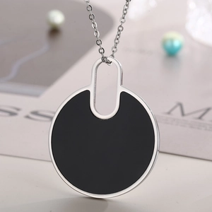Close-up of a silver necklace featuring a minimalist black round pendant on O-chain