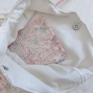 Détail intérieur du sac en toile avec poche dentelle florale et bouton aimanté