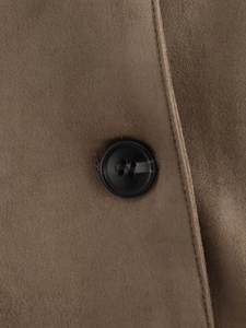 Détail macro du tissu en suédine marron et d'un bouton rond noir sur le vêtement