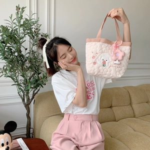 Close-up of pink quilted heart bag with cute puppy embroidery and floral charms