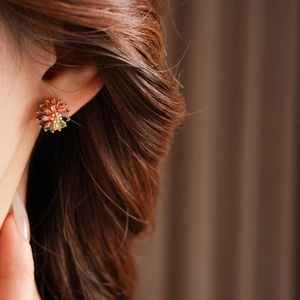 Close-up of elegant flower stud earrings with colorful zircons on a female model