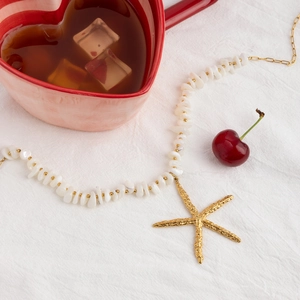 Flat lay of 18K gold plated starfish pendant necklace with natural white stone beads