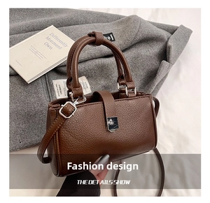 Detail shot of brown lychee texture leather handbag with silver hardware and top handle