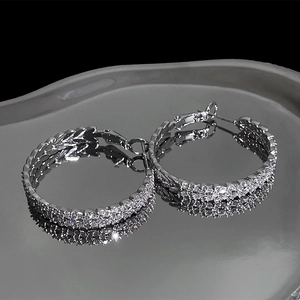 Macro shot of textured silver hoop earrings with shimmering cubic zirconia on dark surface