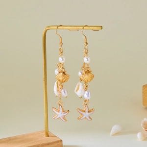 Detailed shot of ocean-style earrings with shells and starfish on a gold display stand