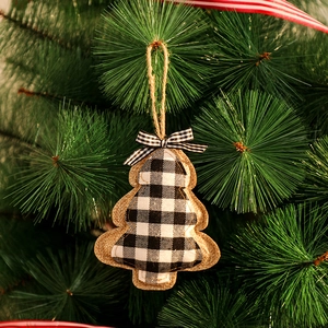 Gros plan d'une décoration de sapin en toile de jute à carreaux sur une branche verte