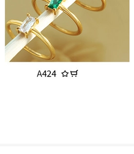 Macro shot of gold rings featuring sparkling green and clear cubic zirconia stones