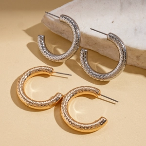 Chic gold and silver C-shape earrings with unique hammered texture on marble base