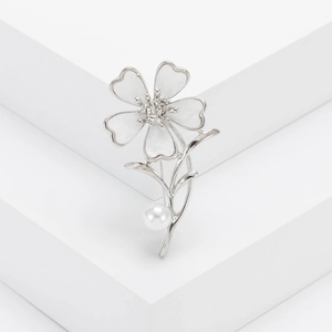 Elegant floral brooch with white petals, center crystal, and pearl on a silver stem
