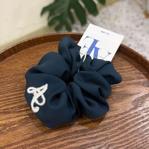 Dark blue velvet scrunchie with white embroidery on a rustic wooden tray with card