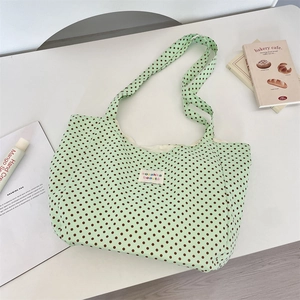 Close-up of light green polka dot canvas tote bag featuring a stitched brand label