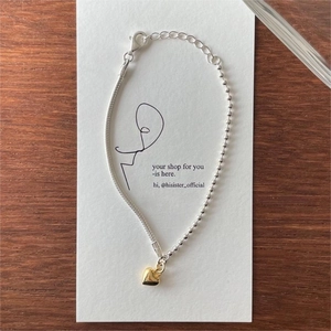Detailed shot of mixed silver chain bracelet with golden heart charm and bead accents