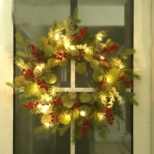 Christmas wreath with red berries, pine cones and LED lights on a glass door