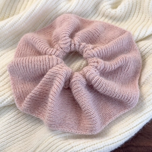 Macro shot of soft pink knitted hair scrunchie with detailed ruffled texture