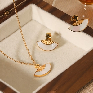 Gold fan-shaped jewelry set with white shell inlay and clover design in luxury box