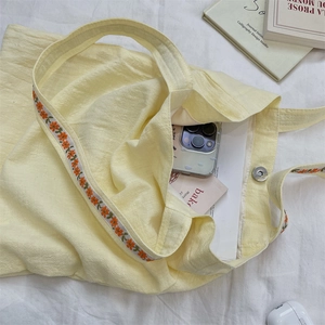 Détail du sac cabas en toile jaune avec broderie de fleurs orange et fermoir magnétique