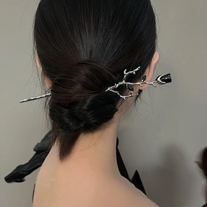 Detail view of a silver rose branch hair pin styled in a modern bun for women