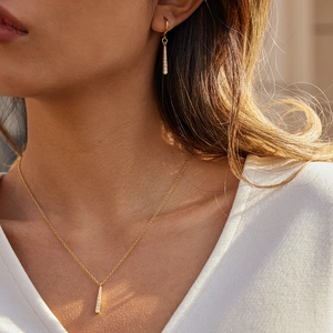 Détails de l'ensemble collier et boucles d'oreilles barre dorée serti de zircons