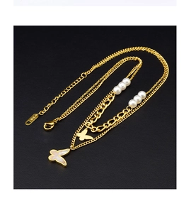 Close-up of double-layer gold necklace with white pearls and butterfly pendants on black leather
