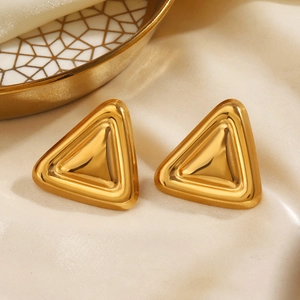 Boucles d'oreilles triangles minimalistes dorées sur fond de satin beige
