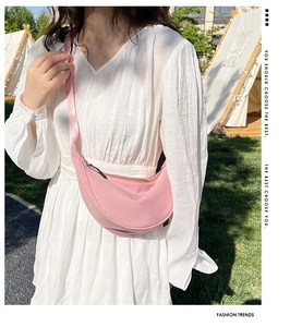 Close-up of pink nylon crescent crossbody bag with adjustable strap in outdoor setting