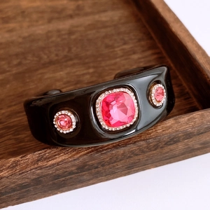 Details von schwarzem Resin-Armreif mit pinken Edelsteinen und funkelnden Diamanten